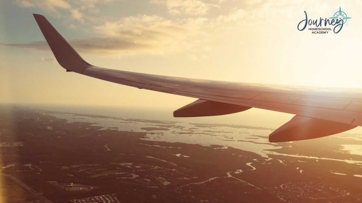 Airplane wing over the landscape at sunset, showing the physics of lift and flight studied in homeschool aerospace lessons with Journey Homeschool Academy
